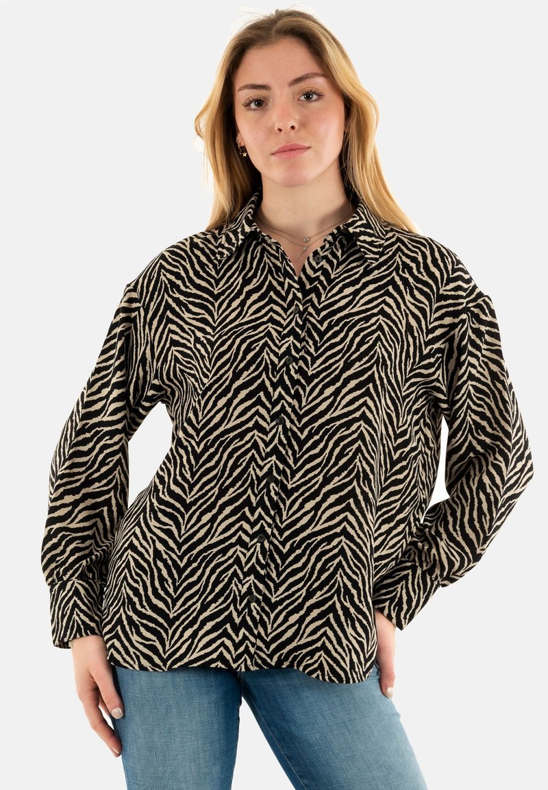 Camicia a stampa zebrica in bianco e nero, con colletto, maniche lunghe e chiusura a bottoni, dal taglio morbido. Tessuto testurizzato.