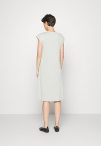 Vestido cinza claro, até ao joelho, com mangas curtas e um corte descontraído. Feito de material macio, apresenta um design simples sem padrões.