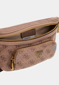 Brun tekstureret stoftaske med gyldent hardware, der har en frontlomme med lynlås og et trekantet logo. Indvendig foring i beige stof.