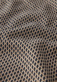 Strickstoff mit einem geometrischen Muster aus abwechselnd navyblauen und beigen Quadraten. Weiche Textur mit einem leichten Stretch.