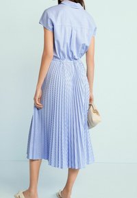 Niebieska i biała sukienka w paski z krótkimi rękawami, wcięciem w talii i plisowanym dołem. G�ładki materiał o luźnym kroju, zestawiona z małą torbą.