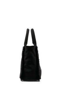 Zwarte tote bag met een gestructureerd oppervlak, voorzien van franje aan de randen en twee platte handgrepen. Het ontwerp is minimalistisch en hoekig.