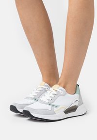 Bílé a šedé tenisky s semišovými akcenty, vybavené texturovaným designem, kulatou špičkou, šněrováním a měkkou podešví.