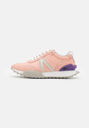 Zapatillas en rosa y gris claro, con un upper texturizado, cordones blancos, un acento en el talón púrpura y una suela gris resistente con pequeñas protuberancias.