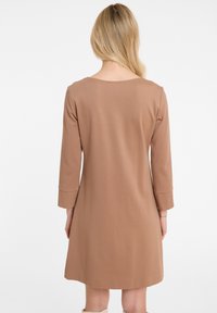 Braunes knielanges Kleid mit langen Ärmeln, glattem Stoff und runden Ausschnitt; hat eine lässige Passform und schlichtes Design.