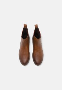 Brown leather ankle boots with a smooth texture, elastic side panels, and pull tabs, featuring subtle stitching details and a sleek shape.