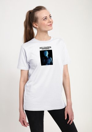 Bílý bavlněný tričko s grafickým potiskem modré postavy s hroty na hlavě, rámované textem "HELL RAISER: INFERNO" nahoře.