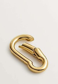 Mosquetón de metal color dorado con un acabado suave, forma curvada y apertura con bisagra para un acoplamiento seguro. Marca grabada claramente visible.