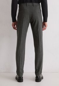 Grijze wollen broeken met een getailleerde pasvorm, met twee achterzakken met knopen, een geplooide voorkant en omgeslagen enkels.