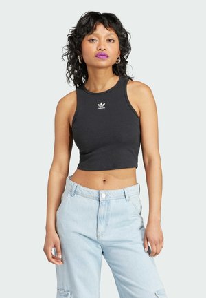 Un débardeur noir court avec une texture côtelée et un logo Adidas blanc sur la poitrine, associé à un jean taille haute bleu clair.