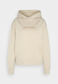 Felpa beige realizzata in morbido tessuto, con tasca a marsupio, polsini a costine e logo Calvin Klein in un beige più chiaro. Vestibilità classica.