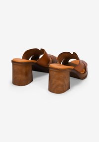 Sandalias de cuero marrón con tacón cuadrado, con un diseño de talón abierto, correas con forma y un tacón texturizado y estriado. El interior presenta un acabado suave.