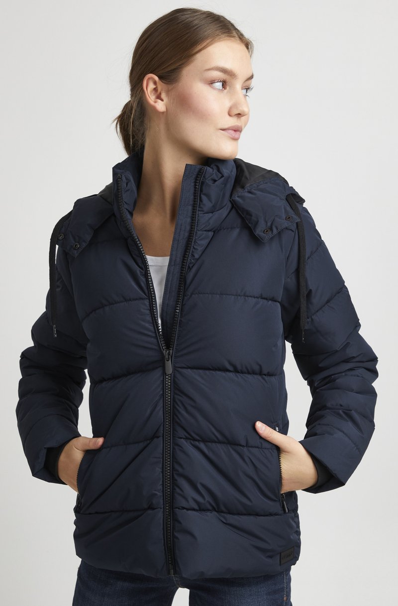 Giubbotto imbottito navy con chiusura a zip e cappuccio regolabile, caratterizzato da cuciture orizzontali e tasche laterali. Tessuto liscio e isolato.