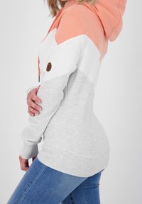 Felpa con cappuccio bloccata nei colori corallo, bianco e grigio; presenta un tessuto grigio testurizzato, lacci di regolazione e una patch con logo marrone.