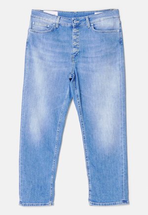 Szmaragdowy satynowy crop top z cienkimi ramiączkami, zestawiony z jasnoniebieskimi dżinsami o wysokim stanie z guzikami i delikatnie zwężanymi nogawkami. Czarne sandały na obcasie.