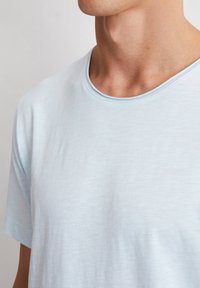 Helles blaues T-Shirt mit kurzen Ärmeln aus weichem, leichtem Stoff, mit rundem Ausschnitt und subtiler Textur. Lässiges Design, ohne Muster oder Akzente.