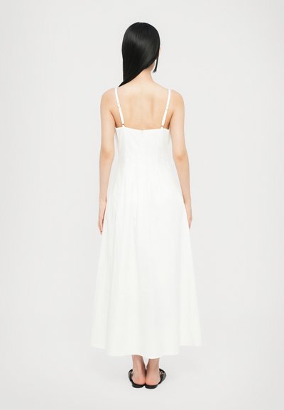 Vestido maxi blanco con tirantes finos, un cuerpo ajustado y una falda acampanada. Presenta un cierre de cremallera en la parte posterior y un diseño minimalista sin patrones.