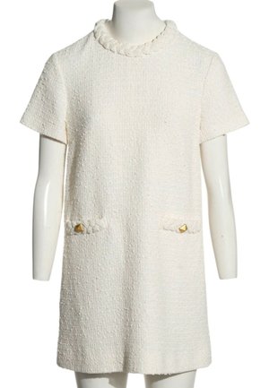Vestido blanco texturizado de manga corta con escote trenzado y dos bolsillos delanteros, cada uno con un pequeño botón dorado en forma de pirámide.