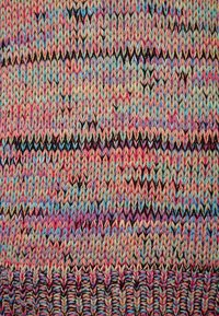 Flerfärgad stickad tyg med ett zigzag-mönster. Färgerna inkluderar rosa, blått, brunt och kräm, med en strukturerad textur.