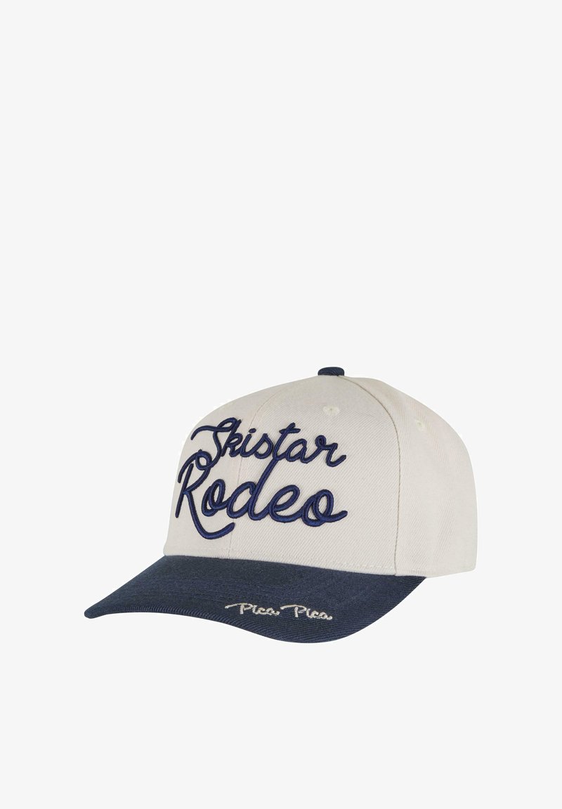 Beisbola cepure gaiši bēšā un tumši jūras zilā krāsā. Priekšpusē ir izšūts "Ski Star Rodeo" tumši jūras zilā krāsā. Tumši jūras zilais vizieris ar baltu šuvumu.