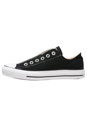 Zapatilla baja de lona negra sin cordones, suela de goma blanca con una franja negra y puntera de goma blanca.