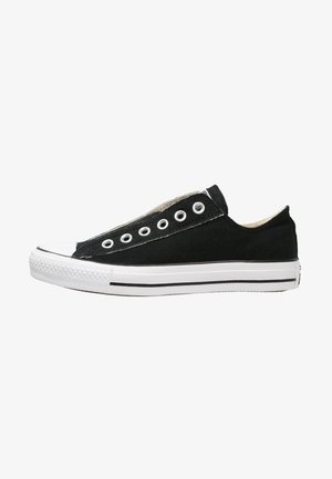 Zapatilla baja de lona negra sin cordones, suela de goma blanca con una franja negra y puntera de goma blanca.