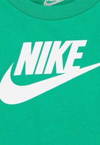 Camiseta de algodón verde con destacado logo en blanco de "NIKE" y diseño de swoosh. Cuello redondo con tejido texturizado.