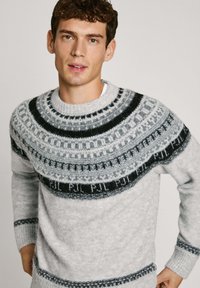 Pull en laine gris avec un col rond. Présente un empiècement à motif en noir et gris, des bords-côtes aux poignets et à l'ourlet, et une texture douce.