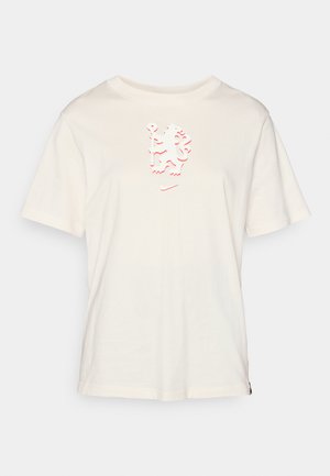T-shirt en coton couleur crème avec des manches courtes et un design graphique texturé rouge sur le devant. Doté d'un col ras du cou et d'un ourlet arrondi.