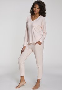 Light pink ribbed sleep set featuring a V-neck long-sleeve top and tapered pants with side pockets. Soft, lightweight, and relaxed fit.