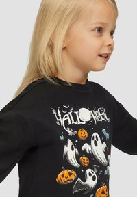 Zwarte sweatshirt met een Halloween-afbeelding van geesten, vleermuizen en pompoenen. Zachte stof, ronde hals en lange mouwen.