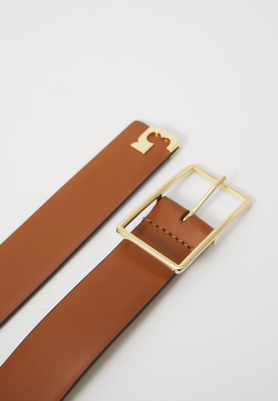 Καφέ δερμάτινη ζώνη με ορθογώνια χρυσή μεταλλική αγκράφα και λεία υφή, με μια τονισμένη θηλιά κοντά στην αγκράφα.