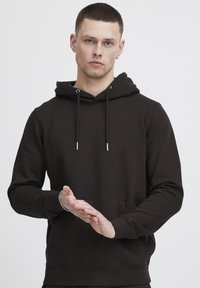 Sweatshirt à capuche noire en tissu doux, avec une poche frontale, des cordons de serrage réglables et des poignets et un ourlet côtelés.