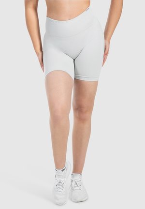 Lichtgrijze high-waisted shorts met een geribde tailleband, een gladde textuur en een getailleerd ontwerp. Gecombineerd met witte sportschoenen.