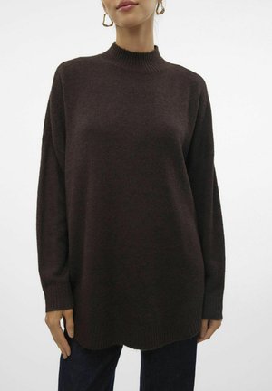 Pull en maille texturée, surdimensionné, marron foncé avec un col montant, des épaules tombantes et des poignets côtelés. Se termine par une légère courbe à l'ourlet.