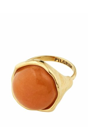 Gold ring with a large smooth round orange stone and "PILGRIM" engraved on the inner band.