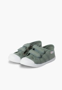 Scarpe di tela verdi con due cinturini in velcro e suole in gomma bianca. Presentano un tessuto testurizzato e strisce laterali per un tocco in più.