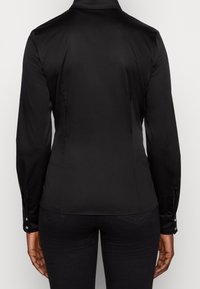 Schwarze Langarmbluse mit glatter Textur, tailliertem Schnitt und Knopfmanschetten. Verfügt über einen klassischen Kragen und einen maßgeschneiderten Rücken.