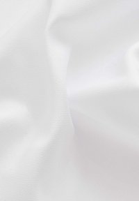 Weißer strukturierten Stoff mit einer weichen, glatten Oberfläche, die subtile Falten und Knitter gegen einen neutralen Hintergrund zeigt.