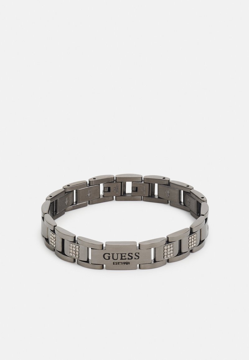 Bracciale in metallo con finitura gunmetal lucida, caratterizzato da maglie rettangolari, tre accenti in cristallo trasparente e un logo inciso centrale.