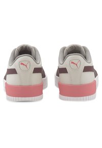 Baskets Puma avec tige beige et marron, accents rose au talon, panneaux en maille texturée, et semelle en caoutchouc blanche. Logo visible sur le talon.