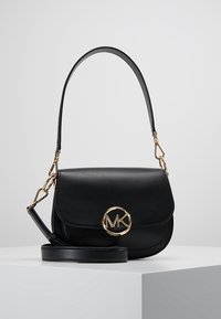 Schwarze Lederhandtasche mit Klappe, goldenem, kreisförmigem Logo-Akzent, verstellbarem Tragegurt und glänzender Oberfläche. Kompaktes Design, geeignet für den Alltag.