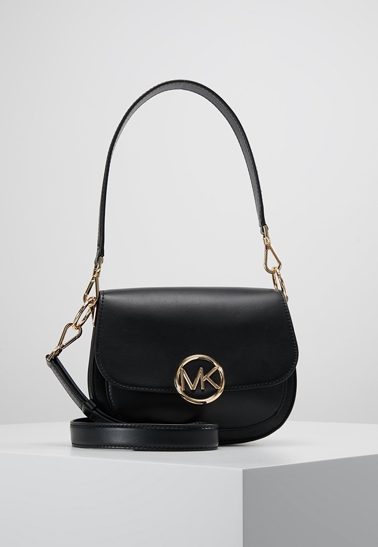Schwarze Lederhandtasche mit Klappe, goldenem, kreisförmigem Logo-Akzent, verstellbarem Tragegurt und glänzender Oberfläche. Kompaktes Design, geeignet für den Alltag.