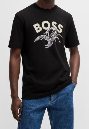 Camiseta de algodón negra con un gran gráfico de una langosta y la palabra "BOSS" en color blanco roto. Mangas cortas y un cuello redondo.