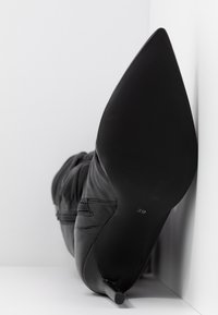 Schwarze Lederstiefel mit spitzem Absatz und Stiletto-Absatz. Mit gewellter Textur und Gummisohle, Größe "39".