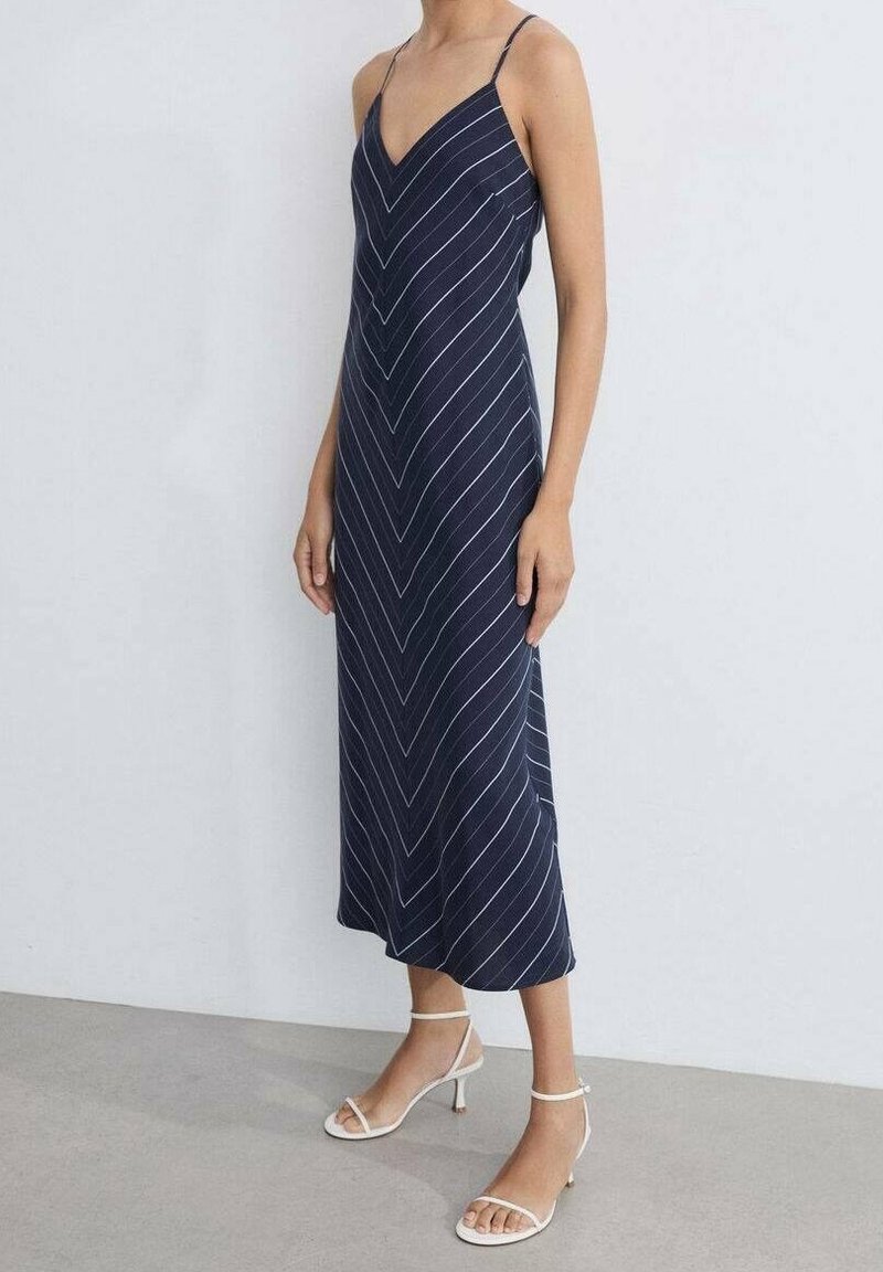 Námořnické midi šaty s bílými vertikálními pruhy, tenkými ramínky a v-výstřihem. V kombinaci s bílými sandály na podpatku.