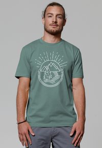 Groen katoenen t-shirt met een witte grafiek van bergen, bomen en zonnestralen. Korte mouwen en een ronde halslijn.