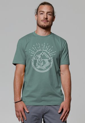 Grünes Baumwoll-T-Shirt mit einem weißen Grafikmotiv von Bergen, Bäumen und Sonnenstrahlen. Kurze Ärmel und runder Halsausschnitt.
