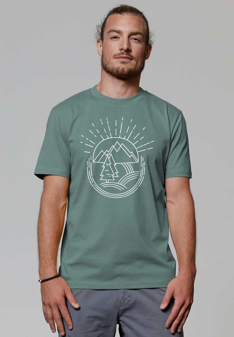 Groen katoenen t-shirt met een witte grafiek van bergen, bomen en zonnestralen. Korte mouwen en een ronde halslijn.