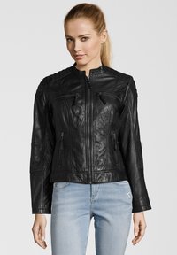 Schwarze Lederjacke mit Reißverschluss, gesteppten Schulterakzenten und zwei Reißverschlusstaschen auf der Brust. Glatte Textur und taillierter Schnitt.